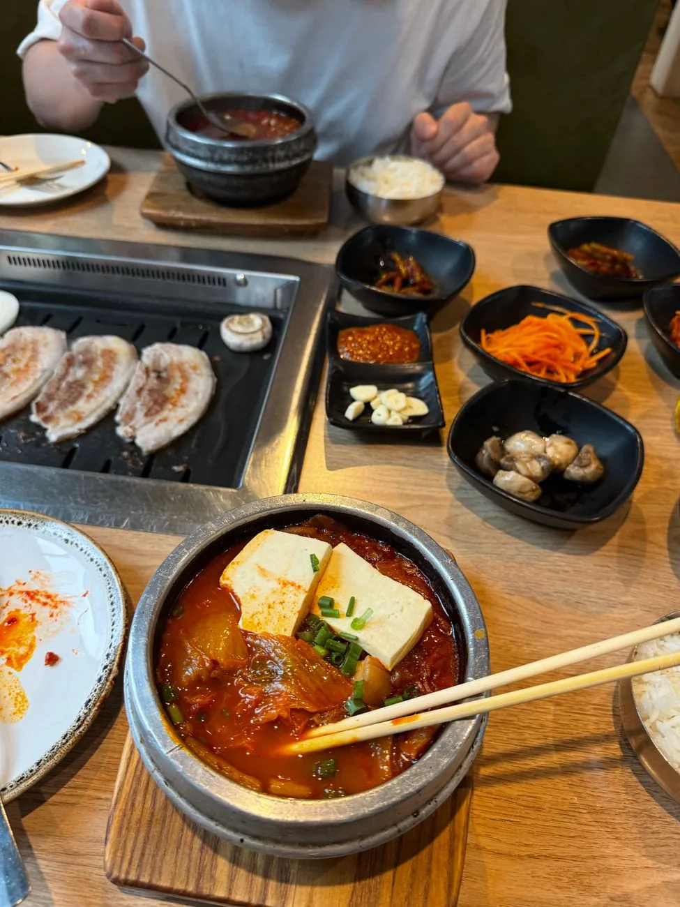 Authentic Korean meal featuring kimchi stew and BBQ pork with side dishes.
