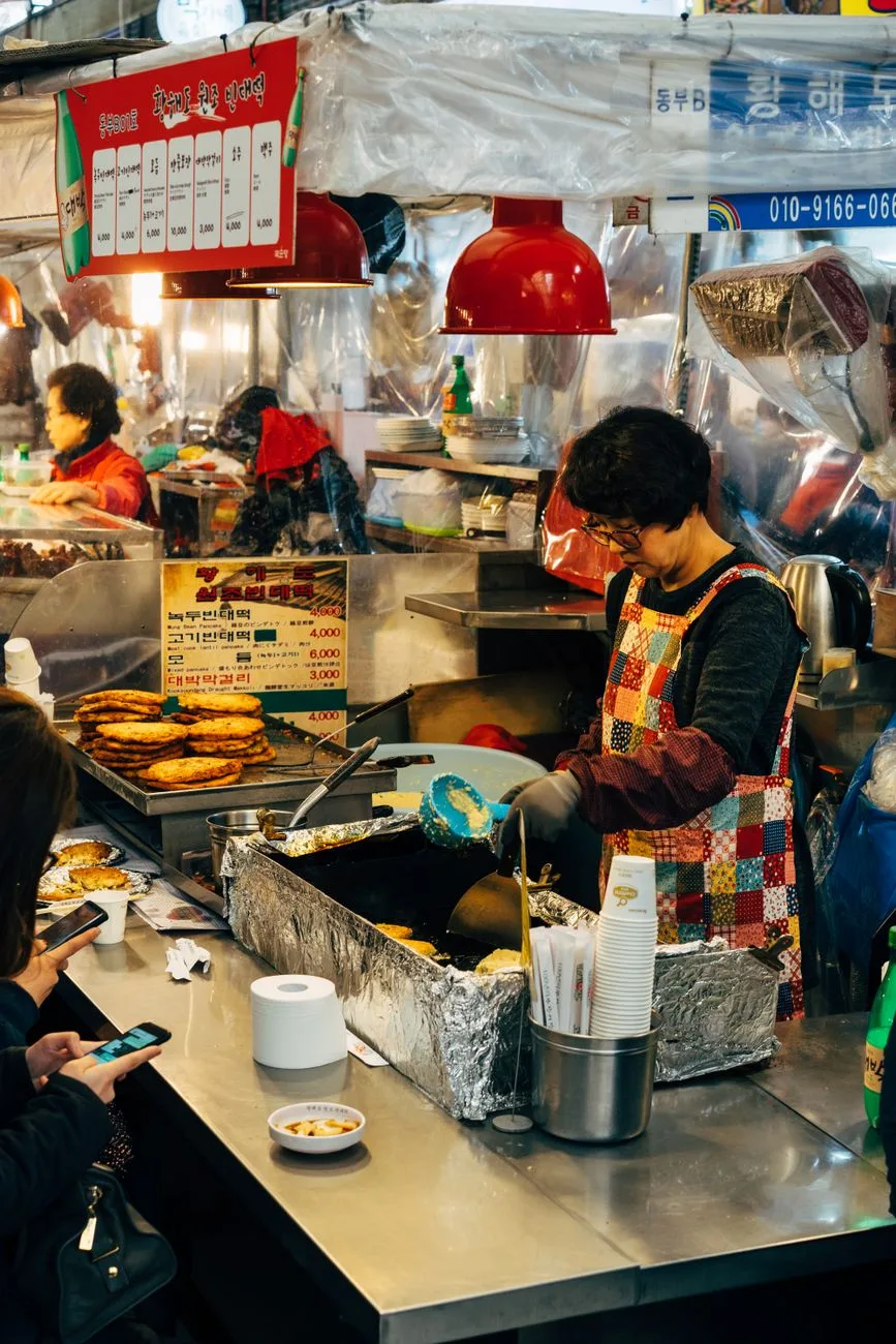 Vibrant street food scene in Seoul showcasing vendor frying traditional Korean pancakes.