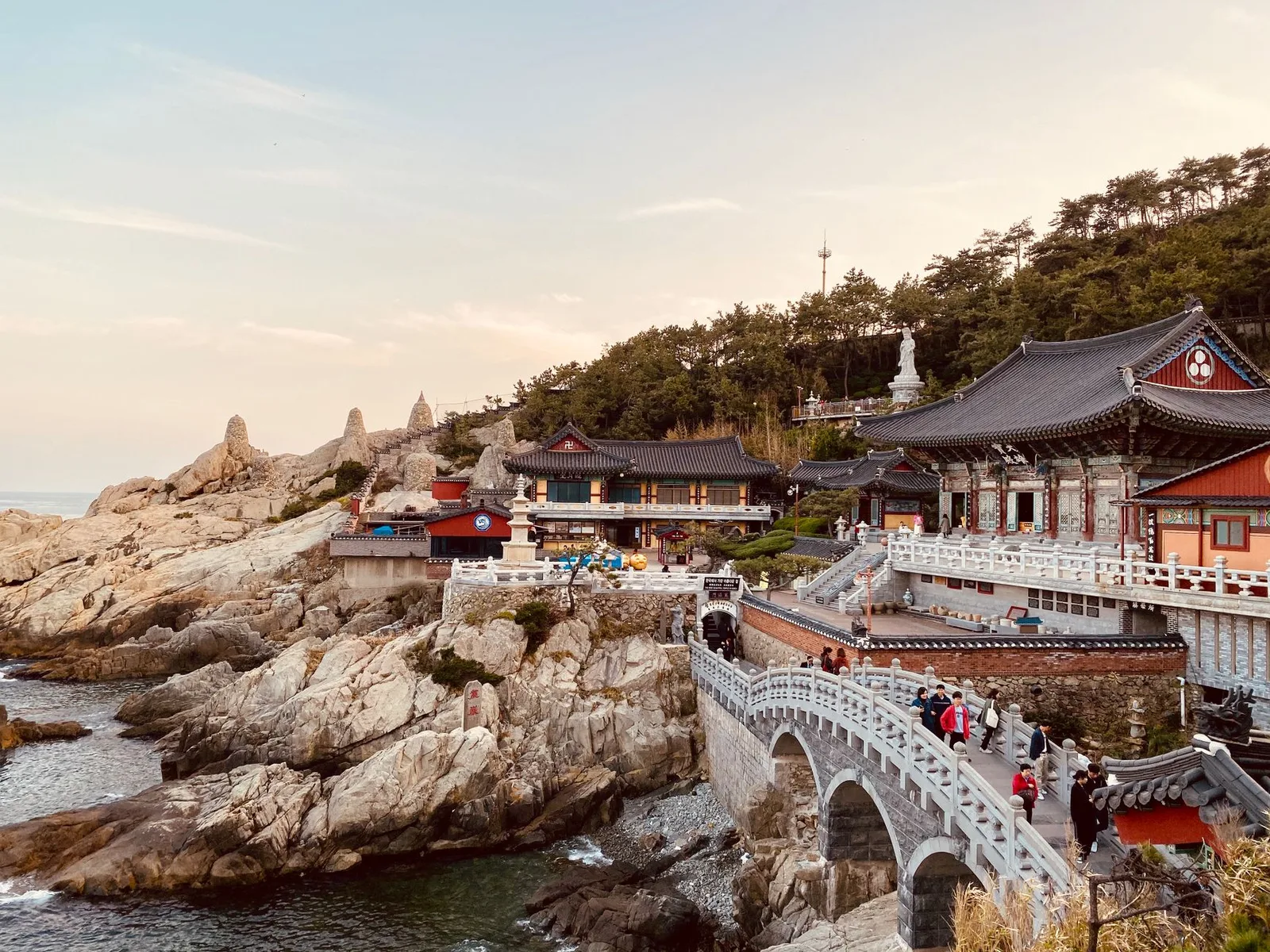 Beautiful Haedong Yonggungsa Temple on a rocky coastline in South Korea at sunset.
