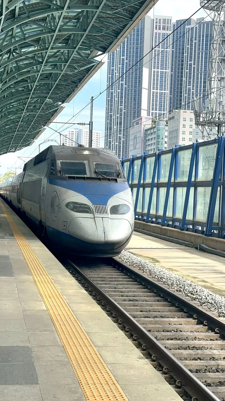 Dynamic shot of a high-speed train at a modern city station in South Korea.