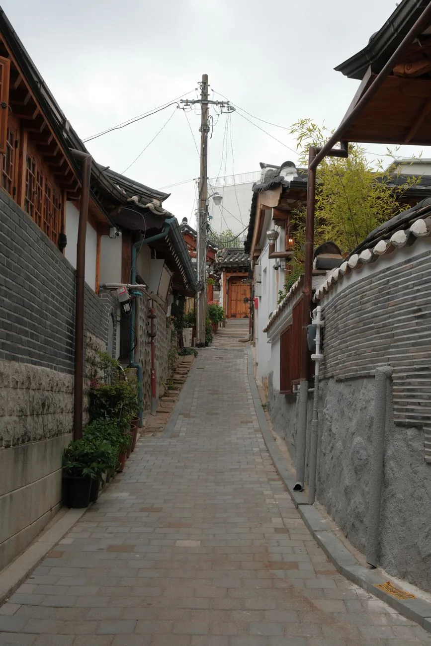 Charming view of a narrow alley in Bukchon Hanok Village, Seoul, showcasing traditional Korean architecture.