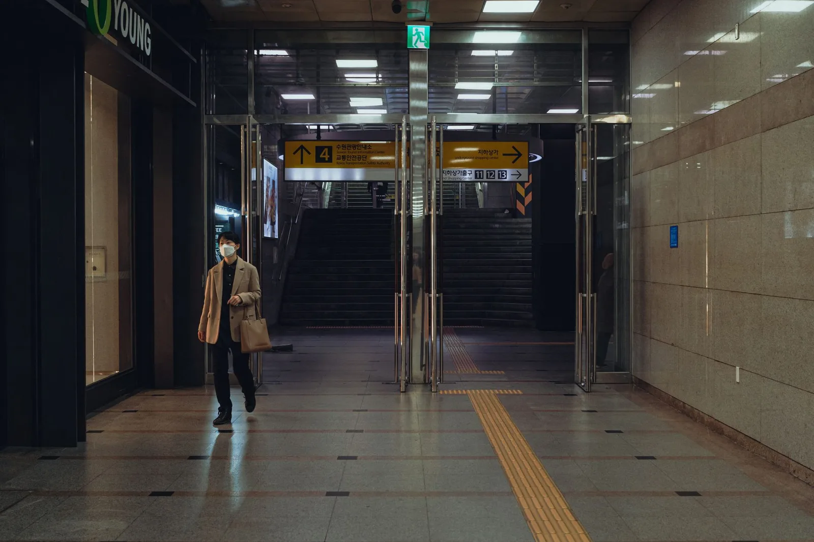 A person walking through a Seoul subway entrance at night. Urban scene with empty corridors.