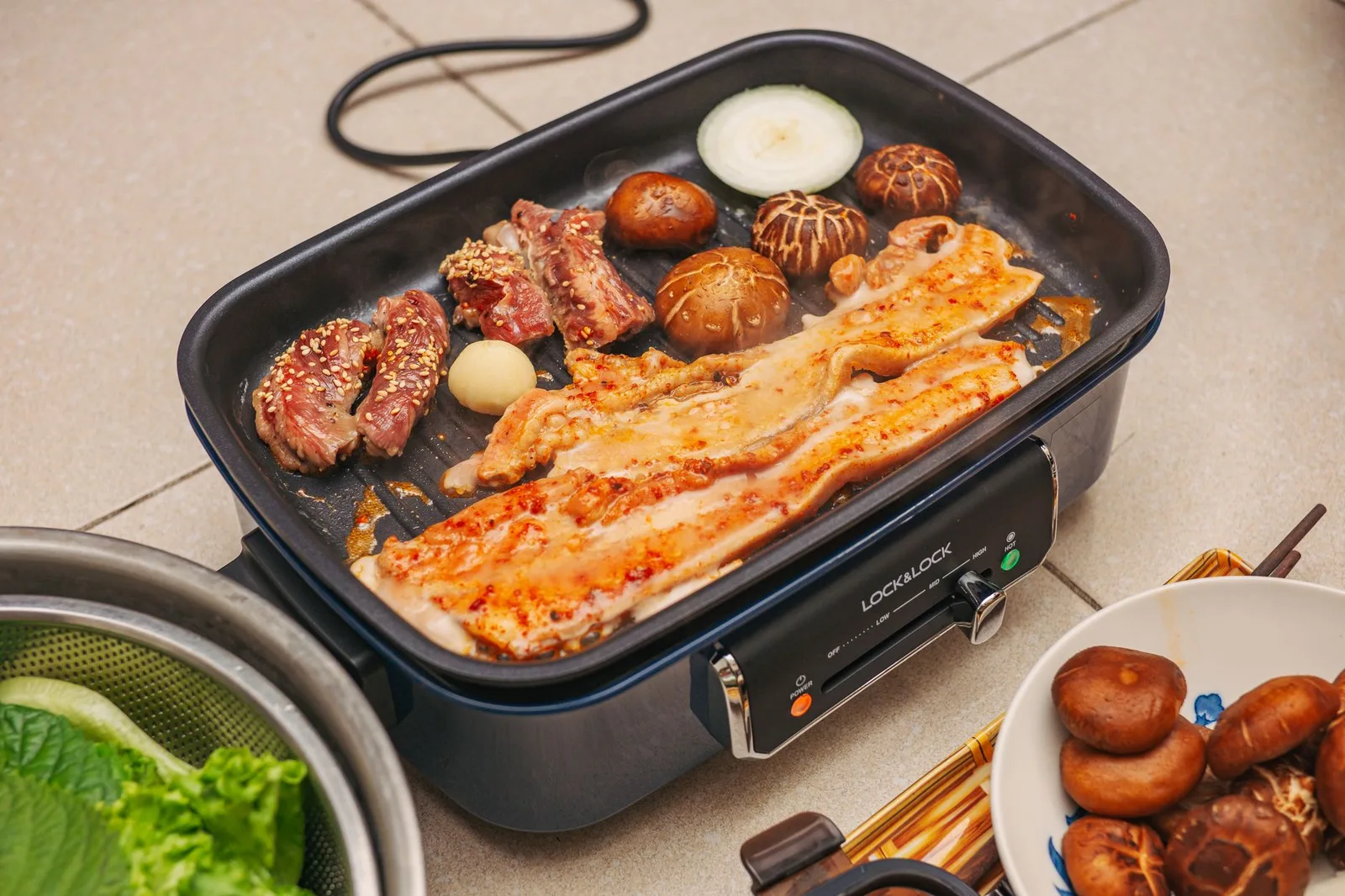 Korean BBQ with pork belly, mushrooms, and vegetables grilling on a pan. Perfect for traditional food lovers.