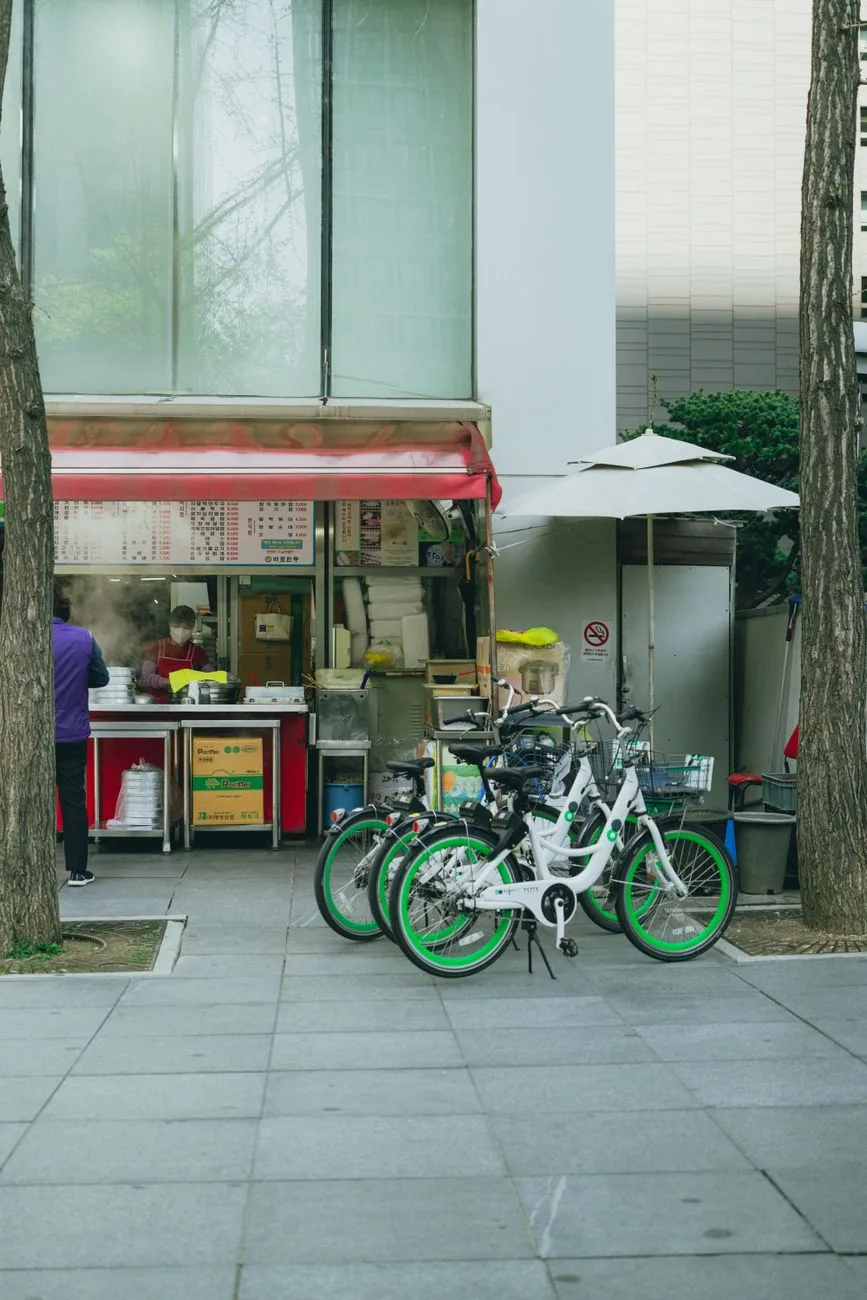 Seoul street scene with bustling food stall and parked rental bicycles, capturing local lifestyle.