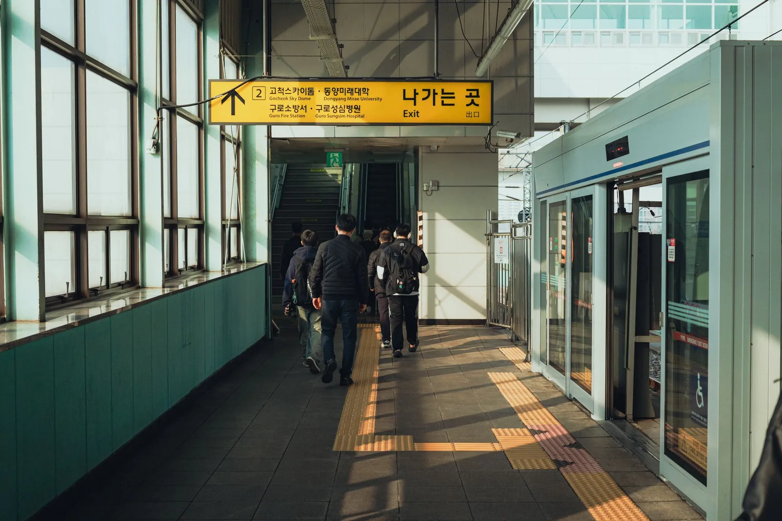 Commuters walking towards an exit at a Seoul subway station, capturing everyday city life.