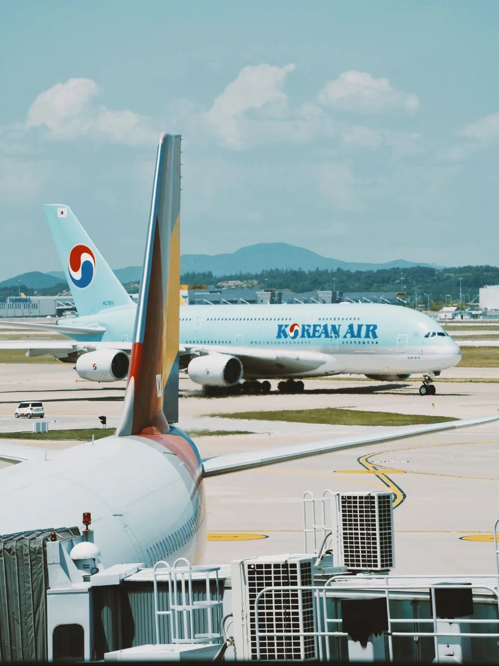 Two Korean Air planes on the tarmac at Incheon Airport under a clear blue sky.