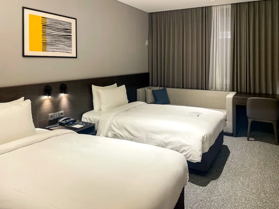 A hotel room with two beds and a desk, illustrating the room-quality side of Seoul hotel value.