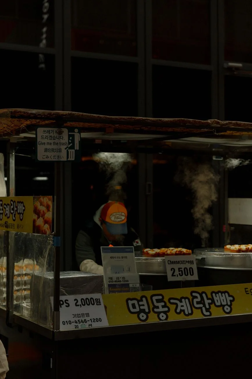 Steaming street food stall in Seoul's market, offering local delicacies under night lights.
