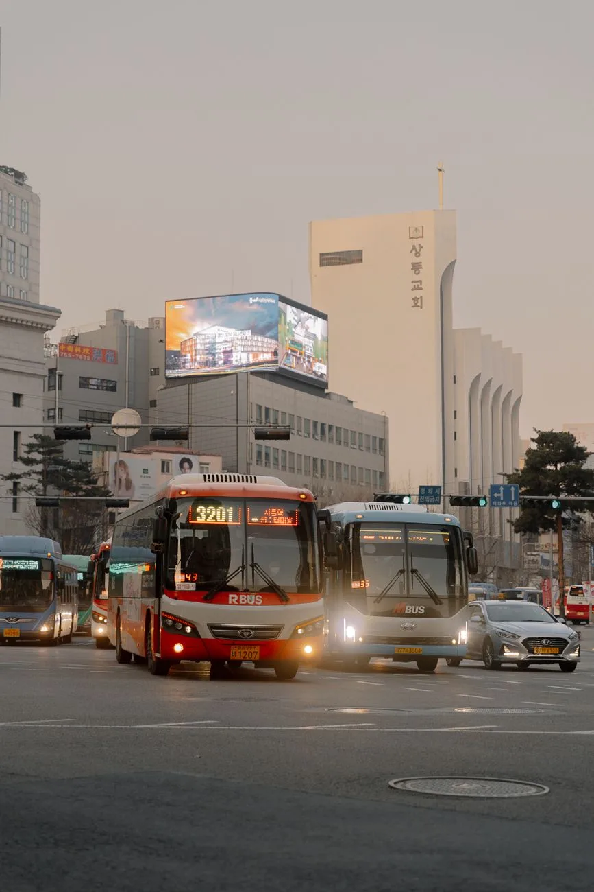 City traffic at a busy Seoul street intersection with buses and cars during the day.