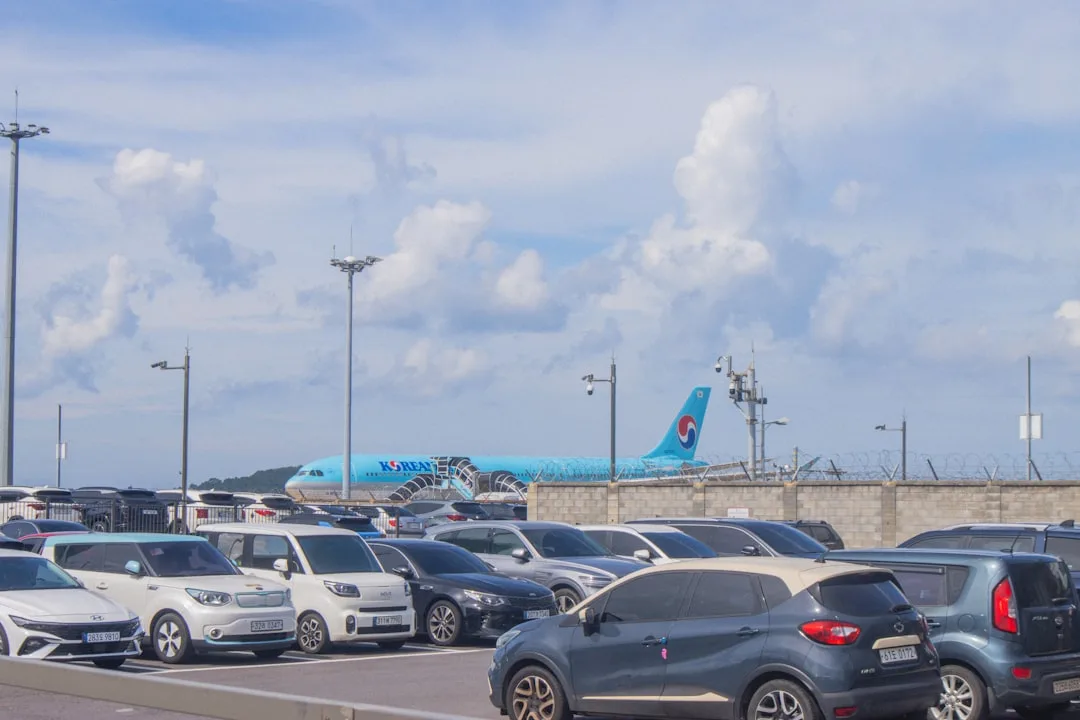 Cars parked with an airplane in the background, illustrating the airport leg of a Jeonju to Jeju trip.