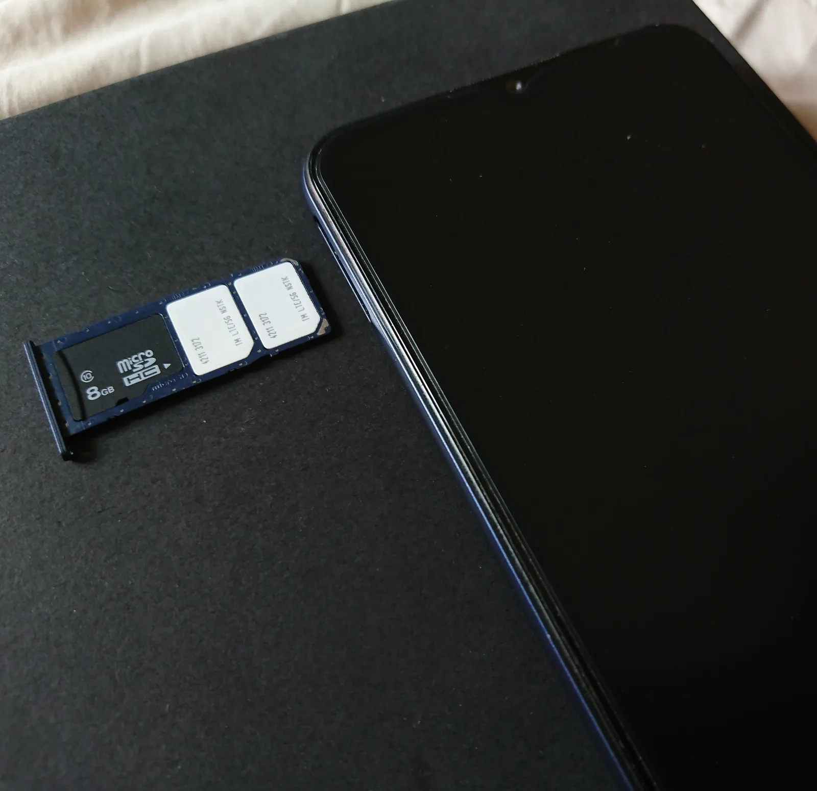 Dual SIM tray with a nano SIM card next to a smartphone