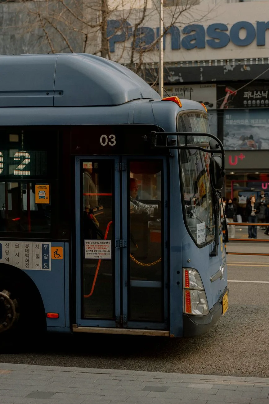 A blue city bus parked on a busy street in Seoul, capturing urban transportation dynamics.