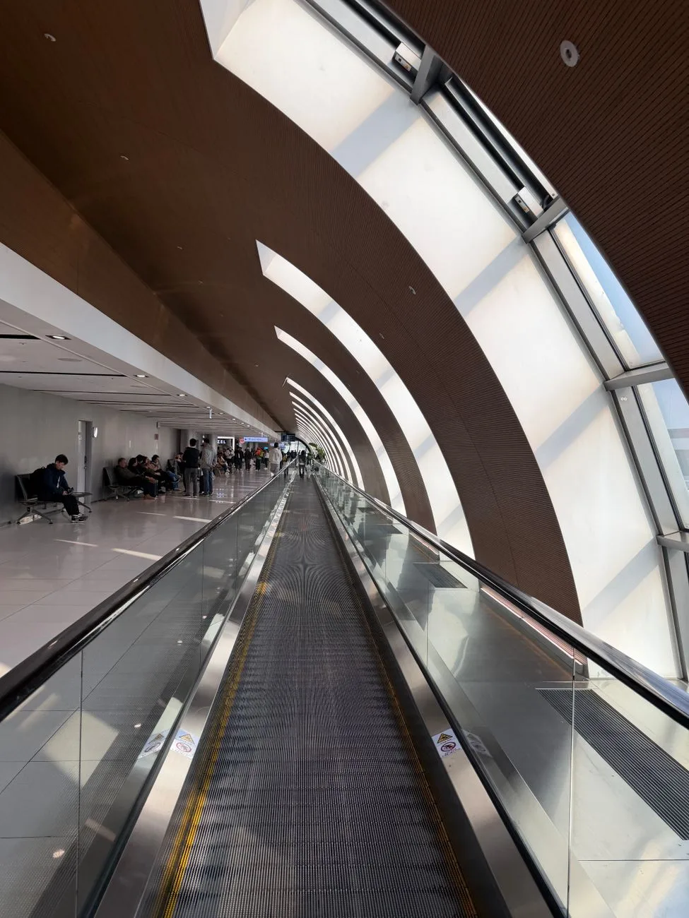 A spacious and modern airport terminal in South Korea featuring a moving walkway with natural lighting.